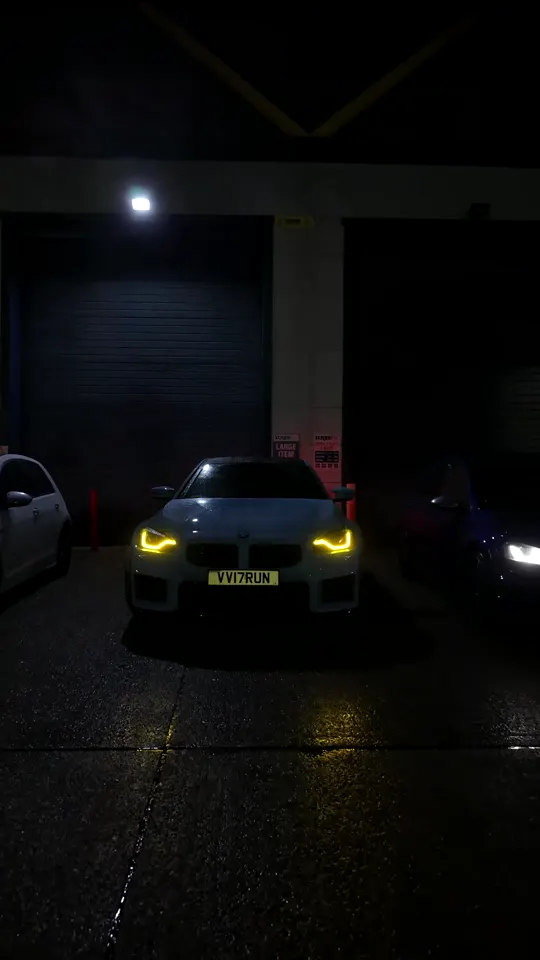 BMW M2 and accompanying cars under workshop lights
